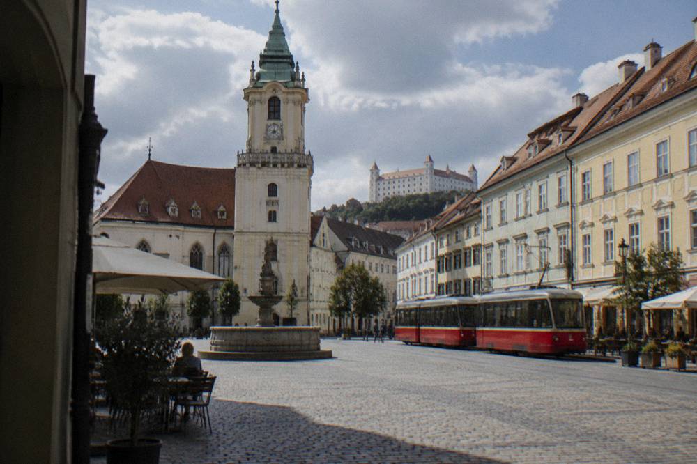 A tram passing colourful buildings on a Bratislava street