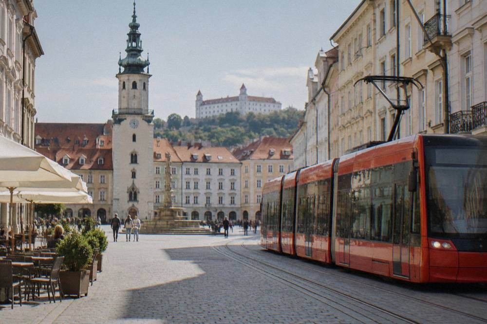 A red tram moving along a street lined with apartment buildings in Bratislava