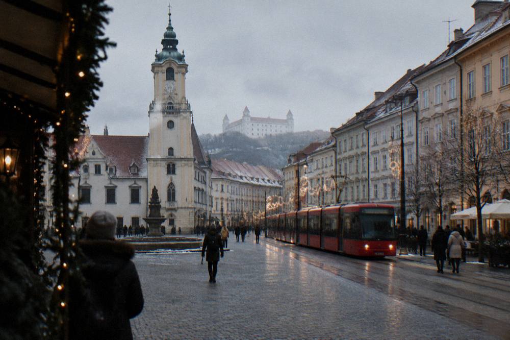 A tram passing through a decorated Bratislava street in the evening