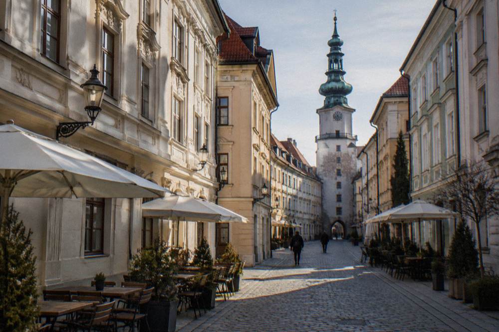 A stone tower with a green copper spire above a narrow old town street