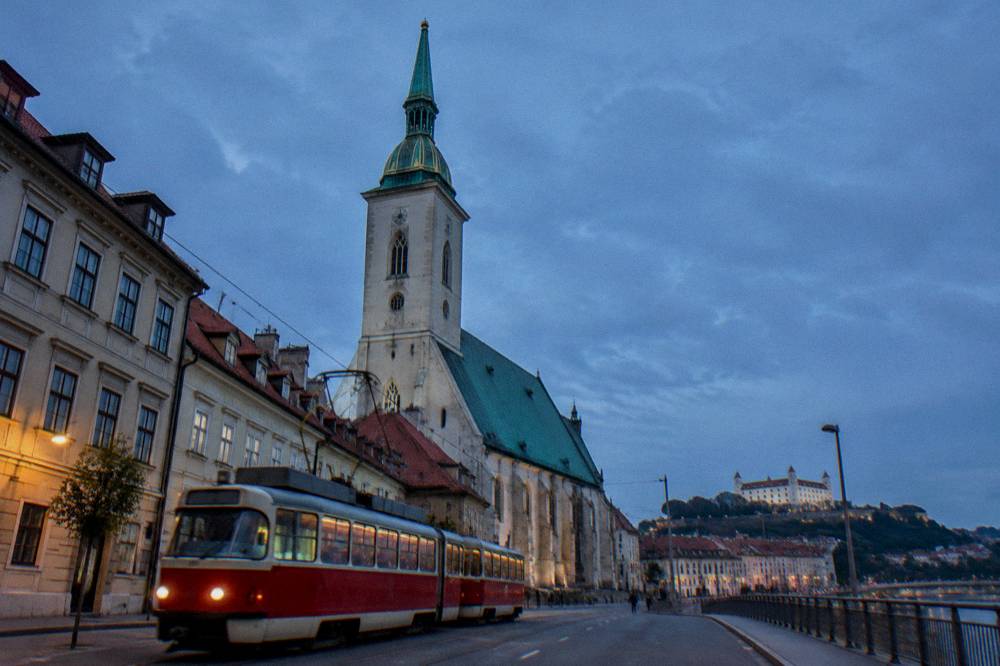 A red and cream tram passing historic buildings on a city street