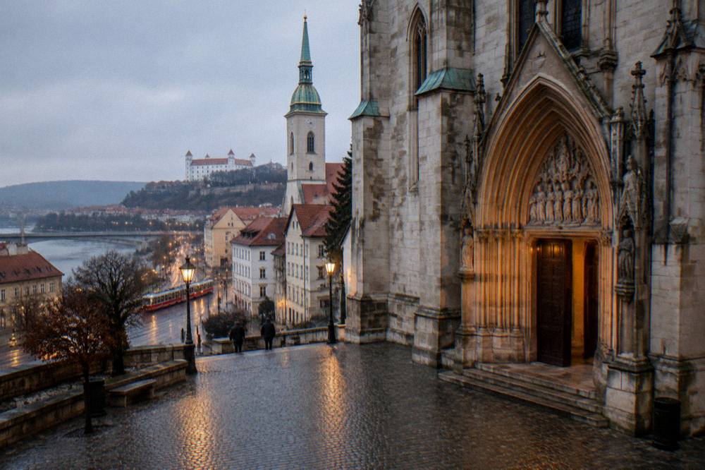 A cathedral doorway seen from a cobbled square in evening light
