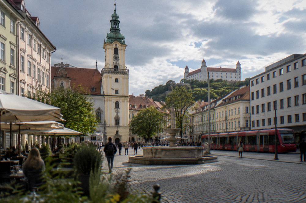 Red tram passing modern buildings on a Bratislava street