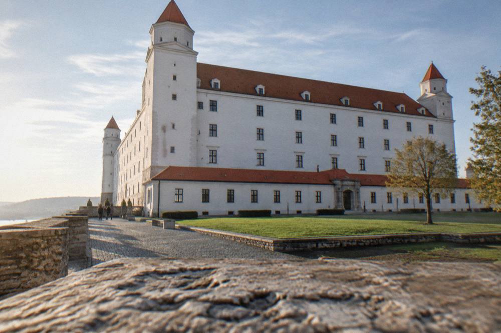The white facade and tiled roofs of Bratislava Castle seen from the courtyard
