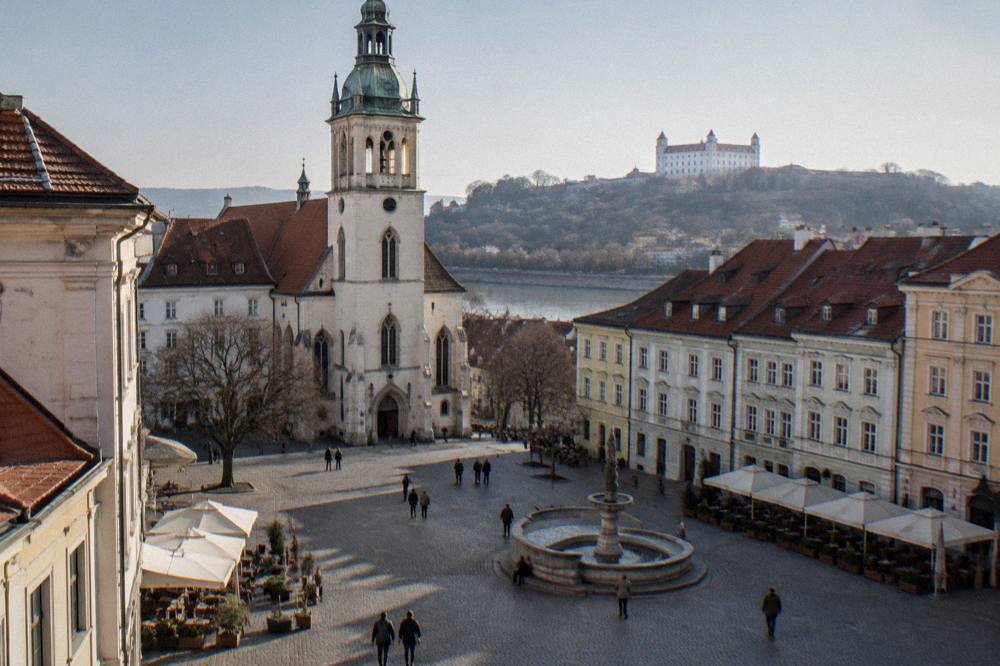 A castle rising above woodland on a hill outside Bratislava under a clear sky