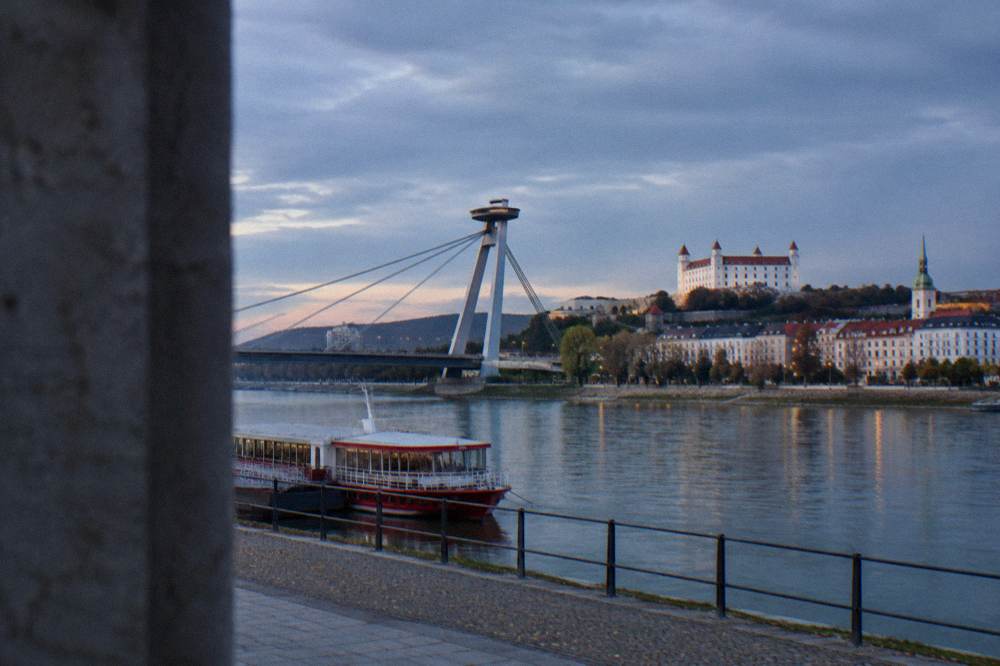 Red Danube river boat moored at a Bratislava riverside pier near the UFO bridge
