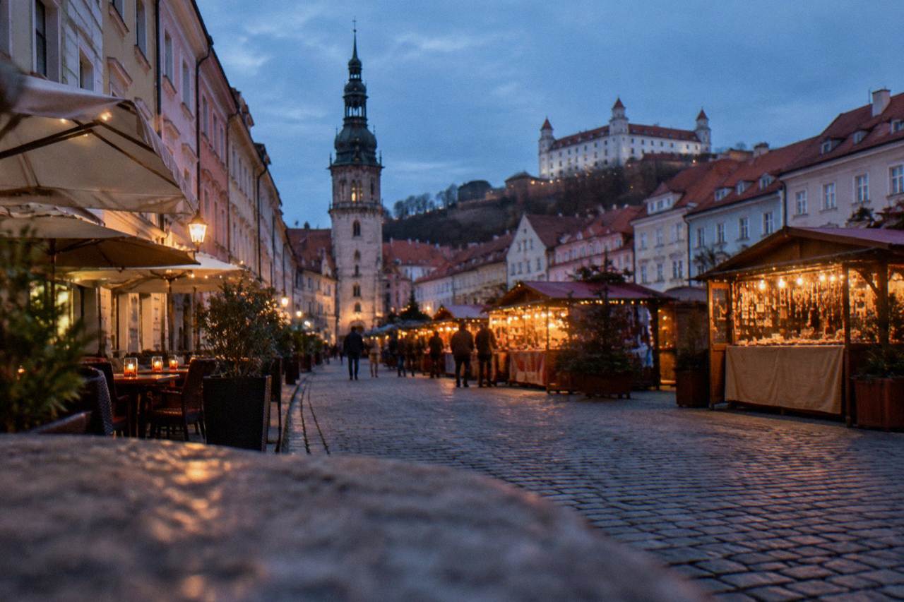Market stalls with glowing lights on a square in the Bratislava Old Town at dusk