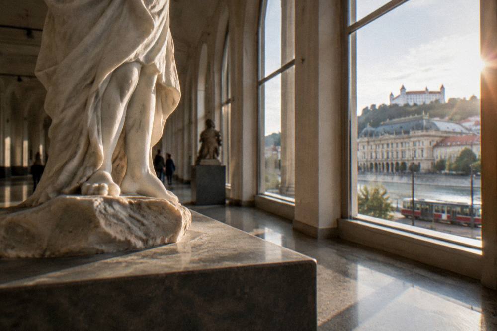 Sculpture displayed in a gallery hallway with tall windows