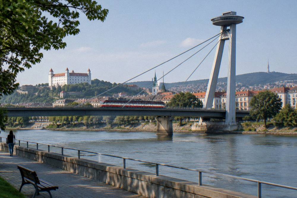 A tram crossing a bridge over the Danube with the UFO tower in the background