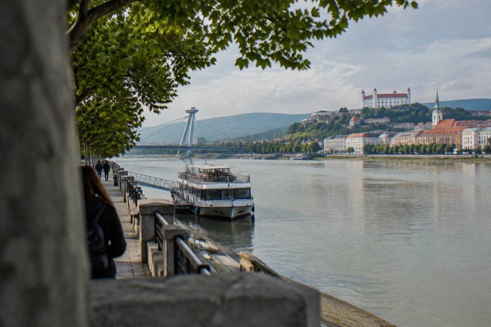 Two cities on opposite banks of a wide river with boats and bridges between them