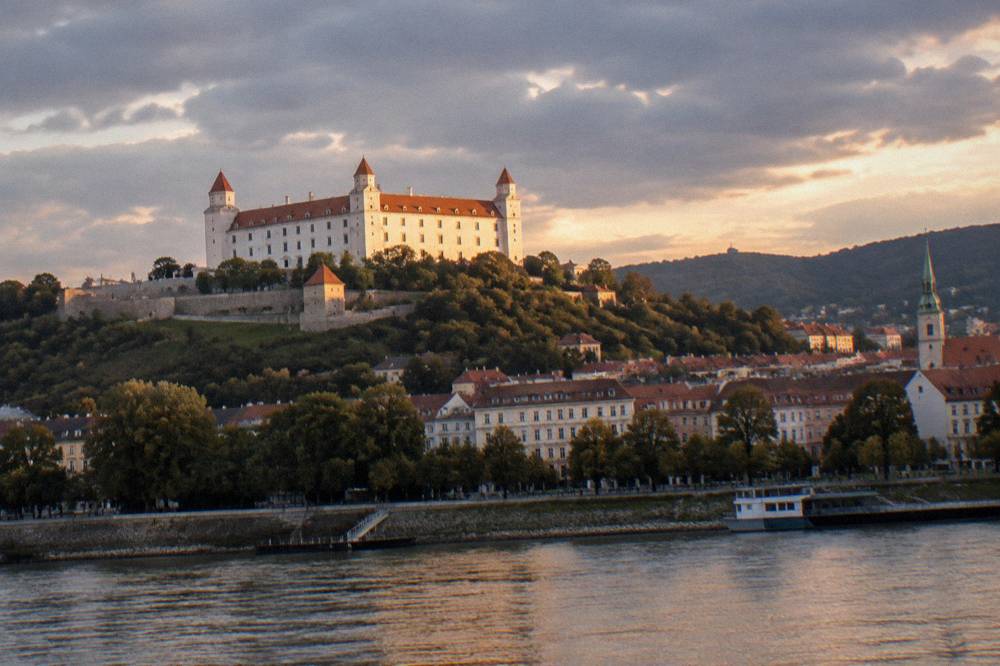 Lit facade of Bratislava Castle above the city at dusk