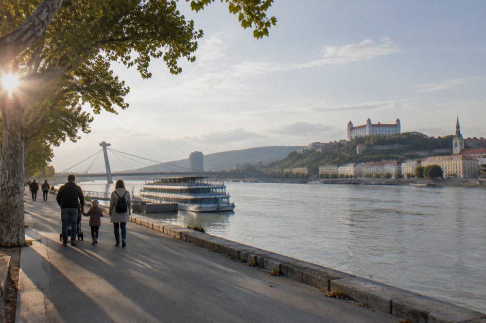 A family walking on a wide path near the Danube riverfront in Bratislava