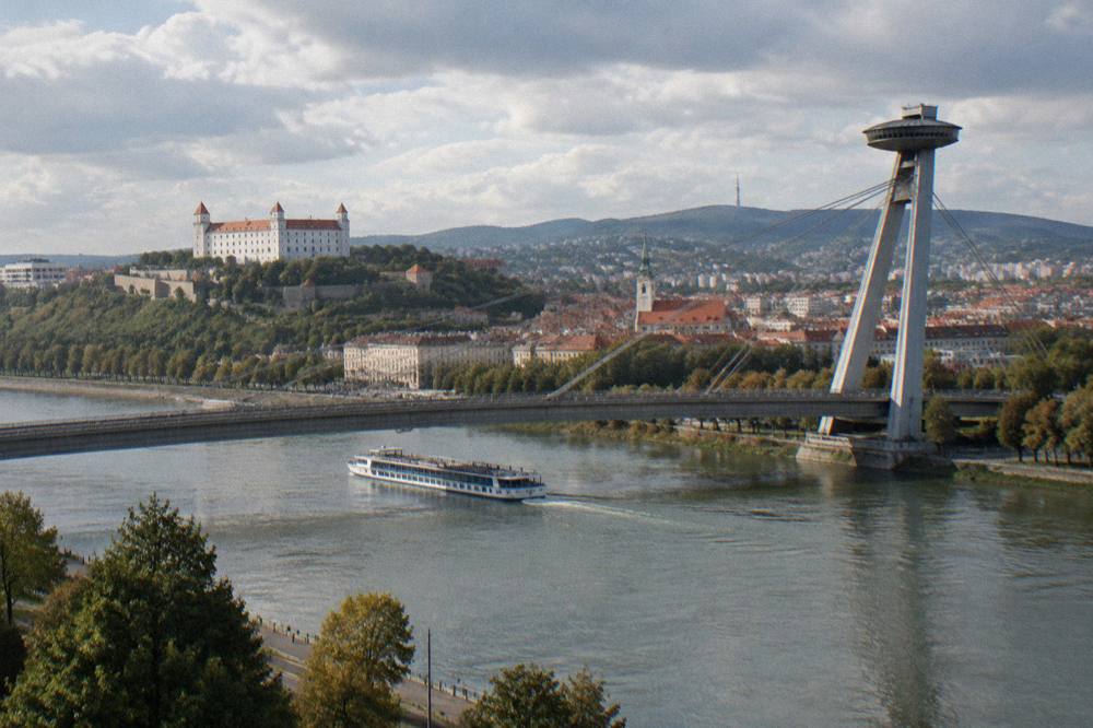 A river cruise boat passing under the UFO bridge on the Danube in Bratislava