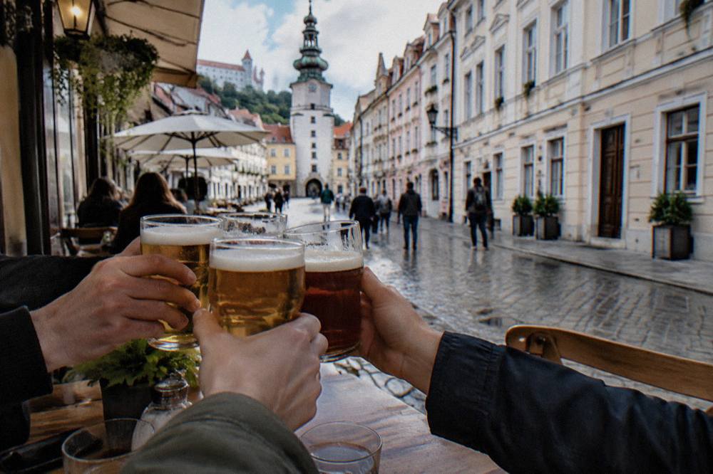 Friends clinking beer glasses at a wooden table in a pub