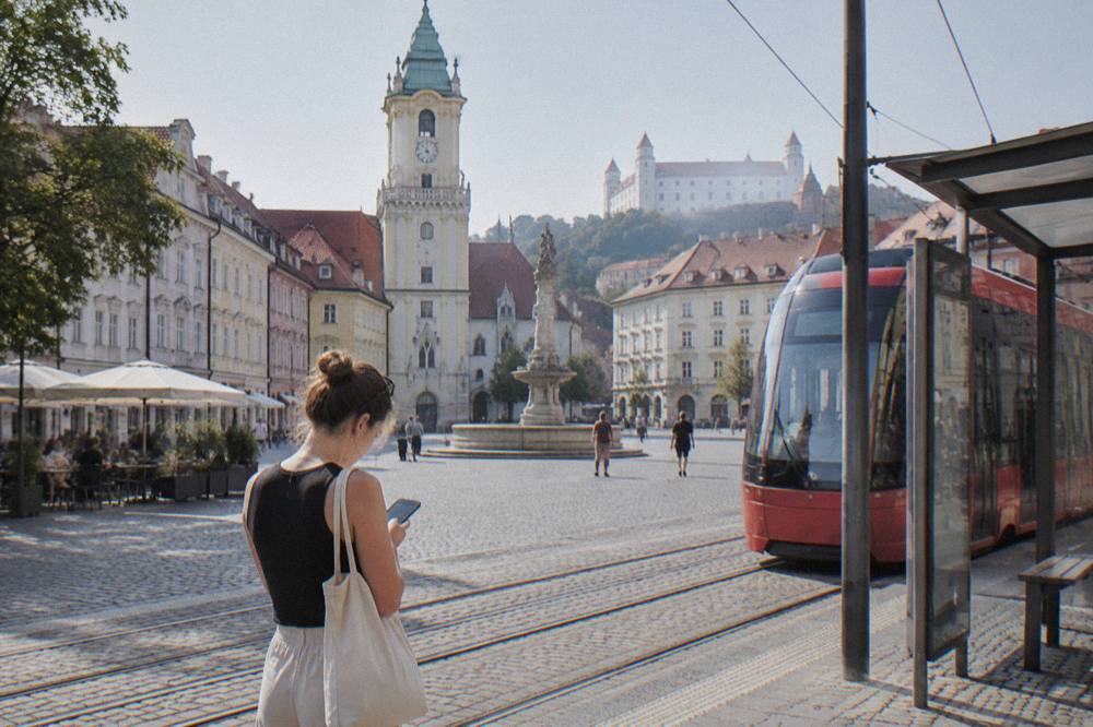 A passenger checking a ride-hailing app beside a tram stop in Bratislava