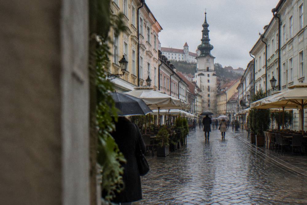 Rainy street in the old town with wet cobblestones and umbrellas