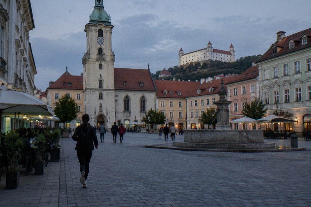 A visitor studying a city map beside the Old Town Hall in Bratislava