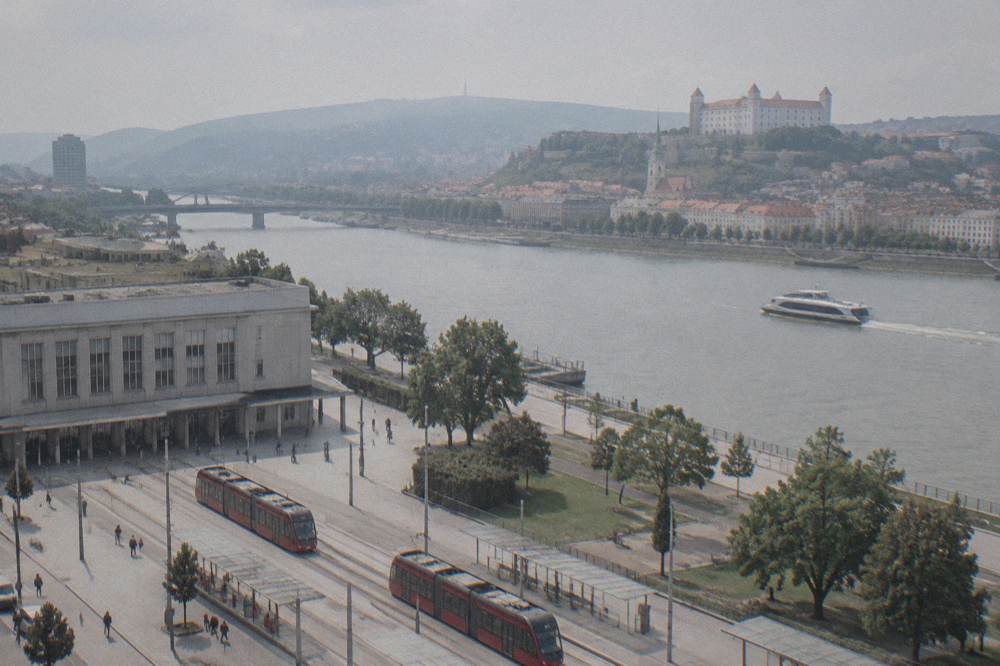 A fast catamaran boat cruising on the Danube with a city skyline behind it