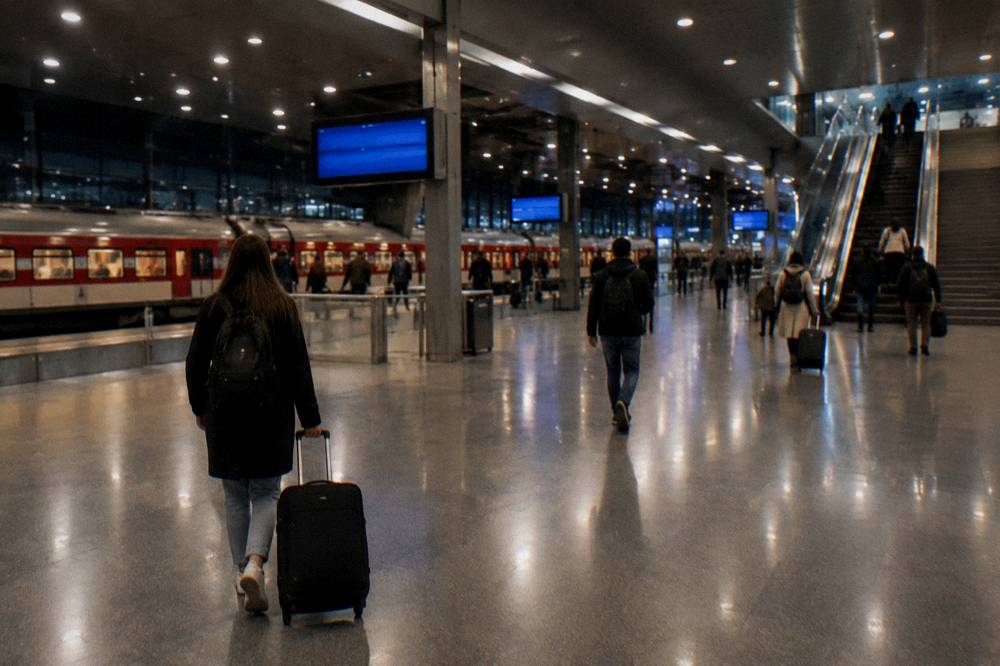 An illuminated railway station concourse at night with a departure board