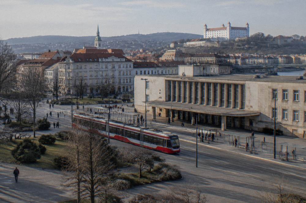 A tram moving along a street in front of a station entrance