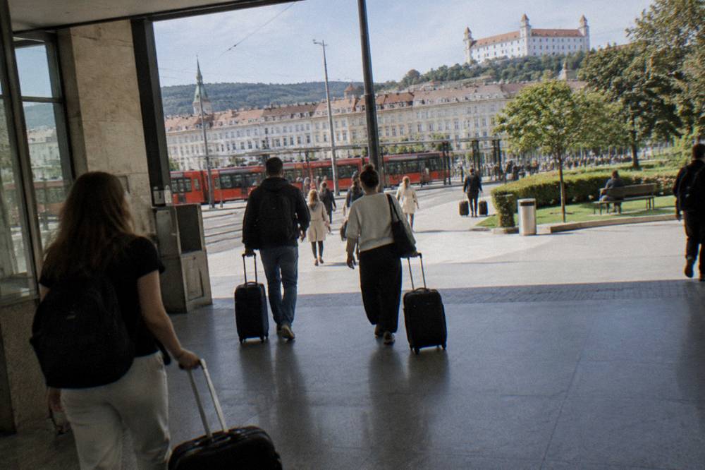 Travellers with suitcases walking through a station concourse toward the exit