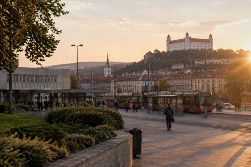 An evening view of an illuminated castle on a hill above a city skyline