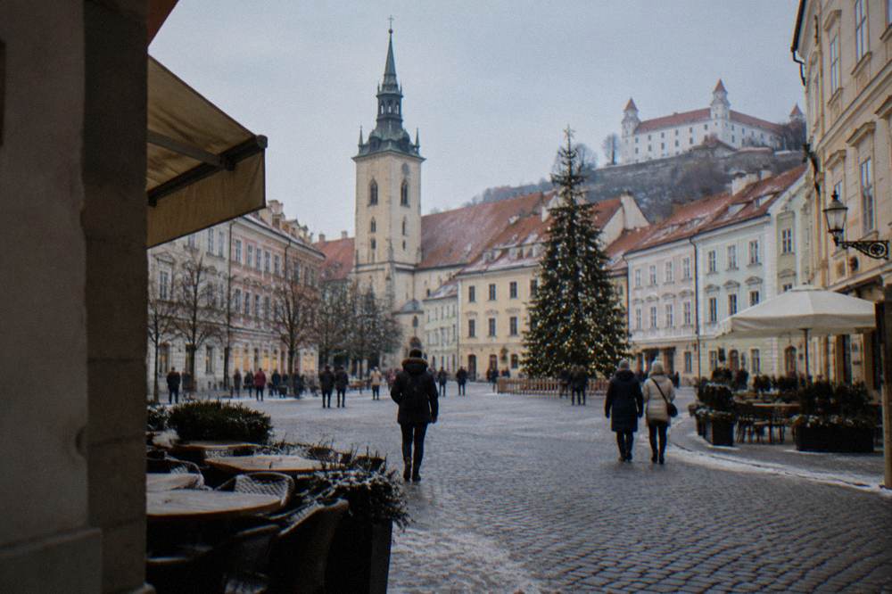 Floodlit Bratislava Old Town square on a winter evening with a Christmas tree