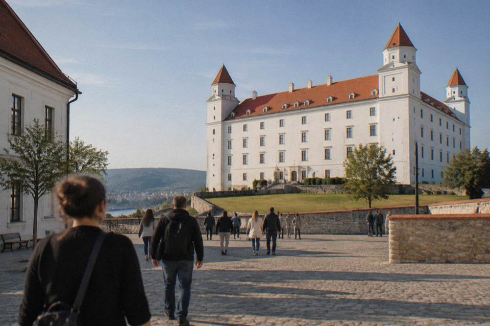 Visitors walking through the courtyard of Bratislava Castle on a sunny afternoon