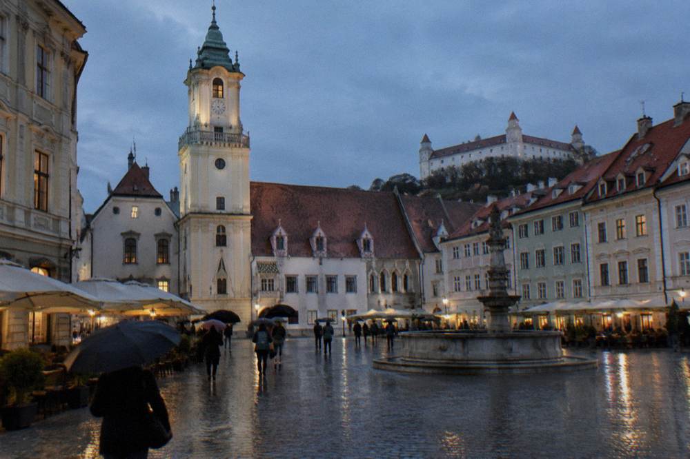 Rain-slicked cobblestones and umbrella-carrying pedestrians in central Bratislava