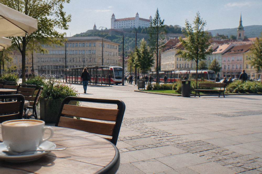 A pedestrian square with pastel coloured townhouses and outdoor cafe tables