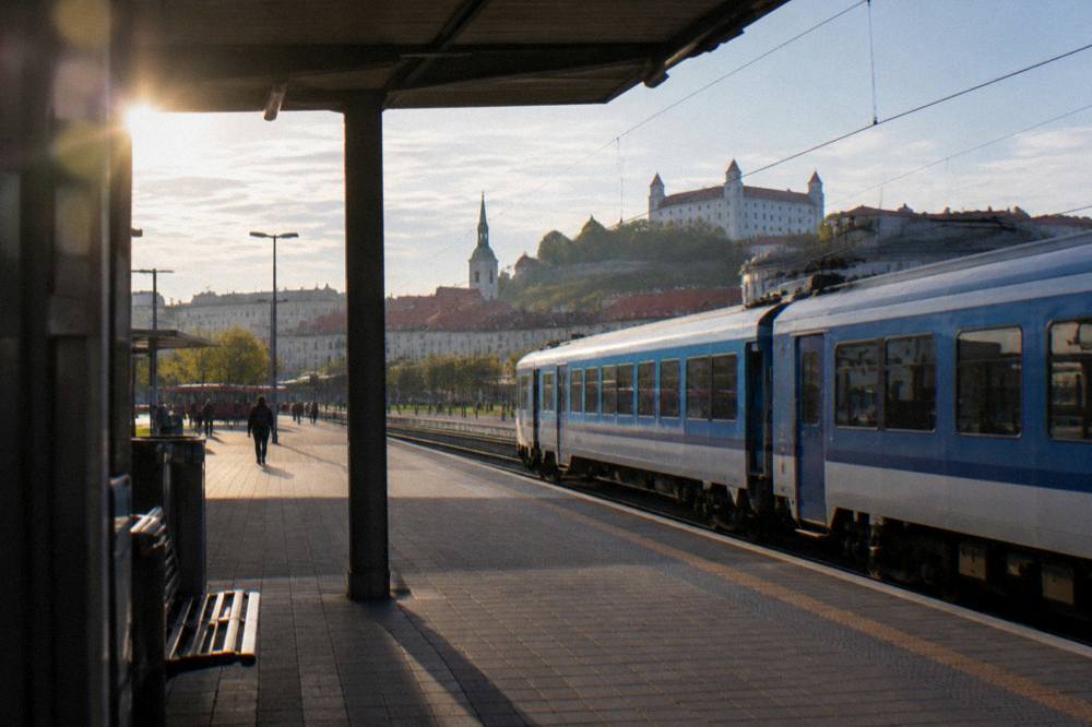 A blue regional train at a station platform under an afternoon sky