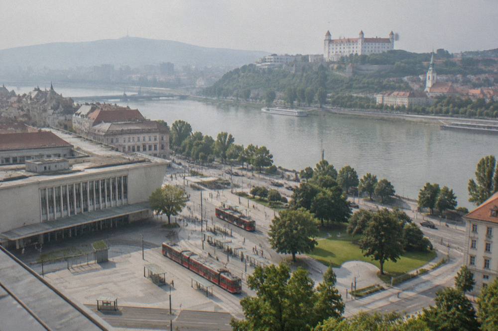 An aerial view of a riverside city skyline with a castle on a hill above a river