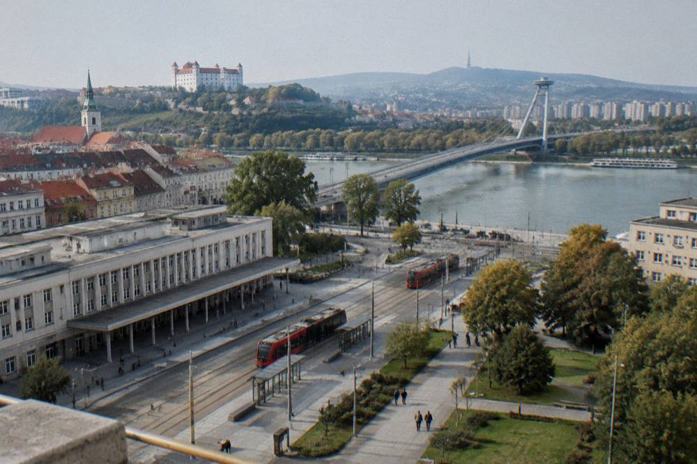 A road bridge crossing a wide river with apartment blocks on the far bank