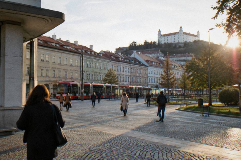 People walking across a cobbled square lined with coloured townhouses