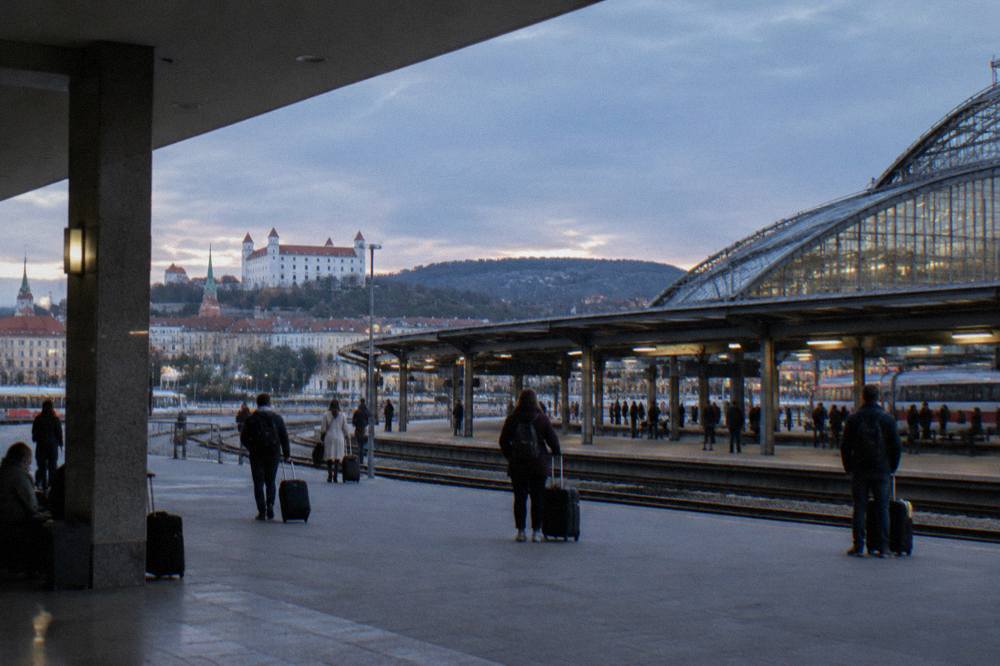 The platforms and glass roof of Bratislava main railway station with travellers waiting