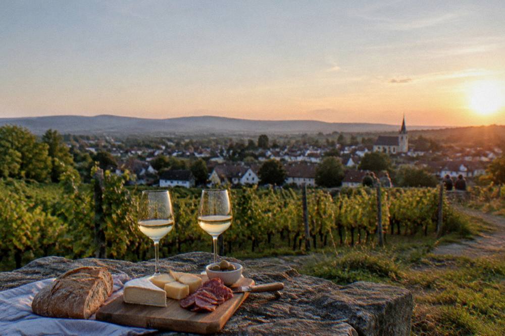 A rustic spread of bread, cheese and cured meat beside two glasses of white wine