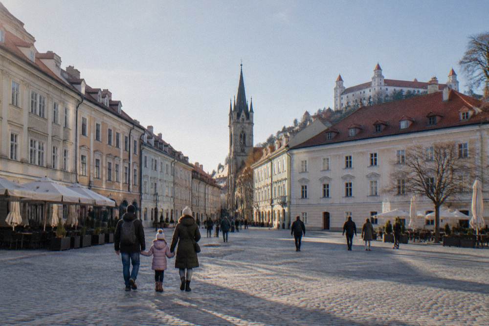 A family walking across a wide square in the Bratislava Old Town