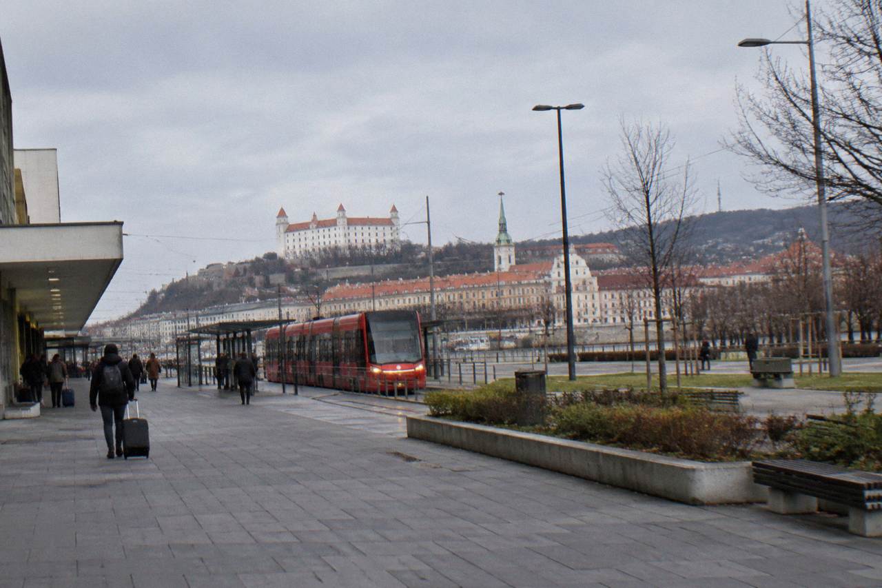 A long-distance coach parked at an airport terminal curb on an overcast morning