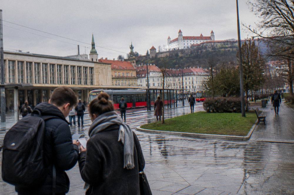 Travellers comparing phones and signs at a transport interchange in a European city