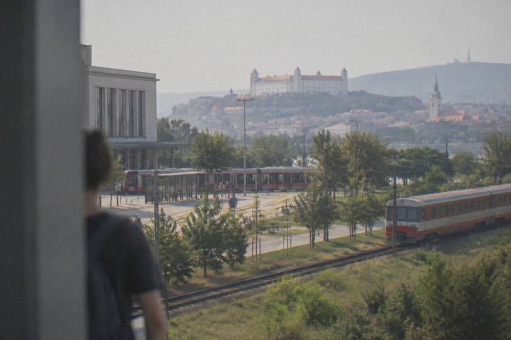 A regional train travelling through open countryside towards a city skyline