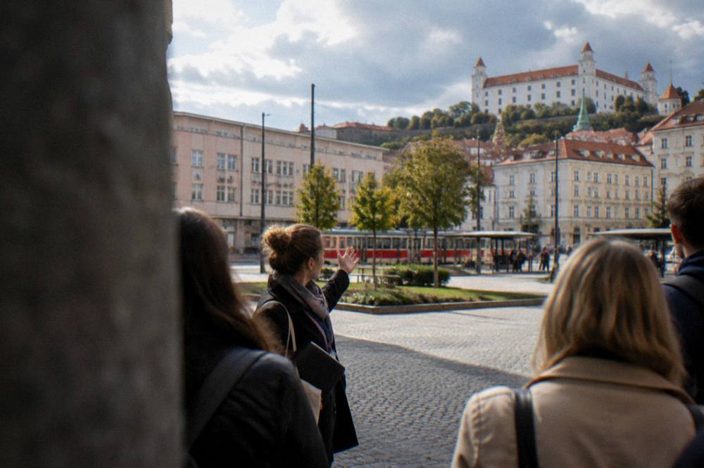 A guide speaking to a small group of visitors on a cobbled city square