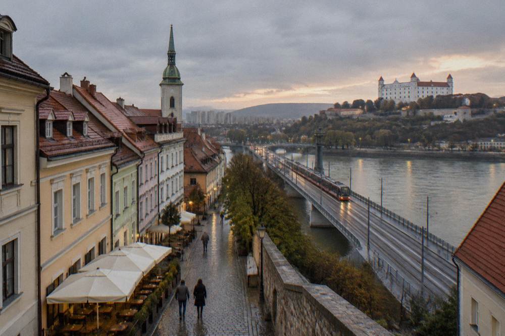 Tram tracks crossing a Danube bridge toward the Petržalka district at dusk