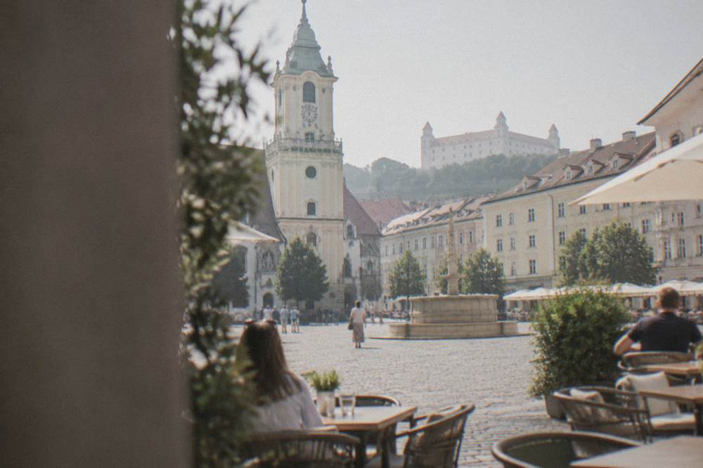 Outdoor restaurant tables on a cobbled square in Bratislava at midday