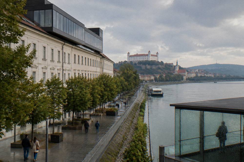 Glass-walled observation deck above the Danube with rain on the windows and grey river views