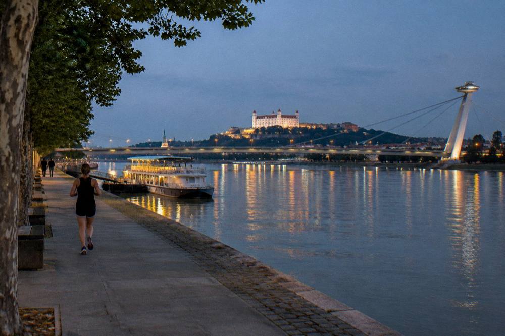 The Danube riverfront with the bridge lit after dark