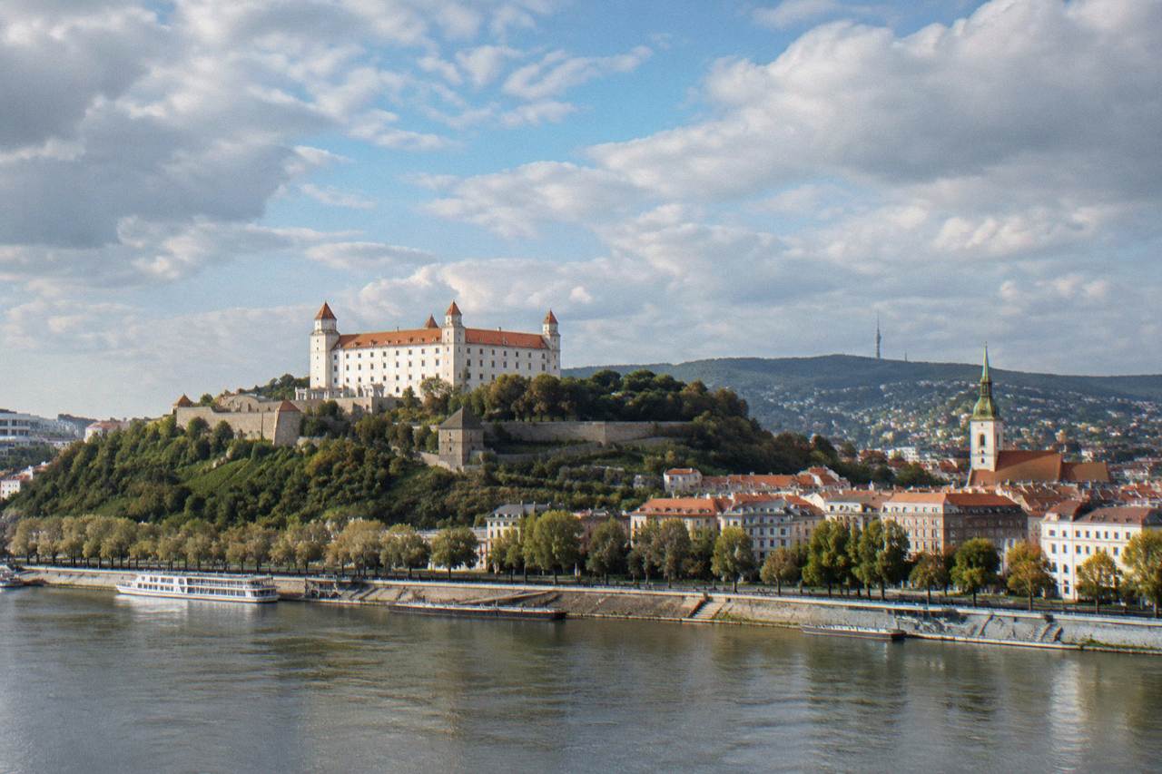 The Danube river flowing past Bratislava Castle on its hill above the city