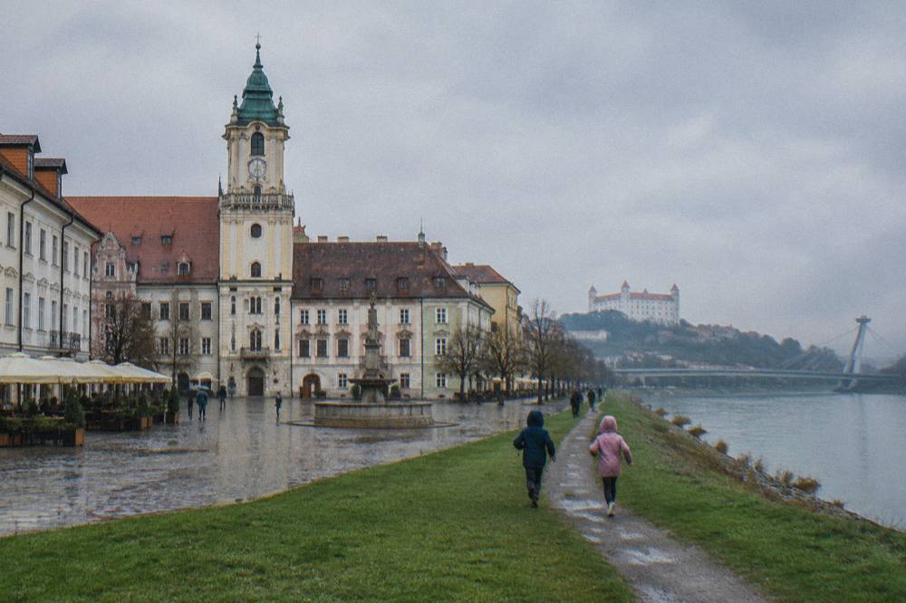 Children running on a grassy riverside path along the Danube in Bratislava