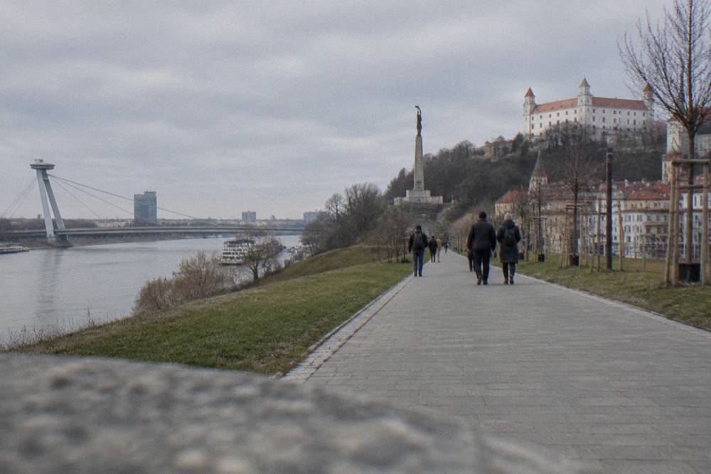 Visitors walking a paved path toward the Slavin memorial with its stone column ahead