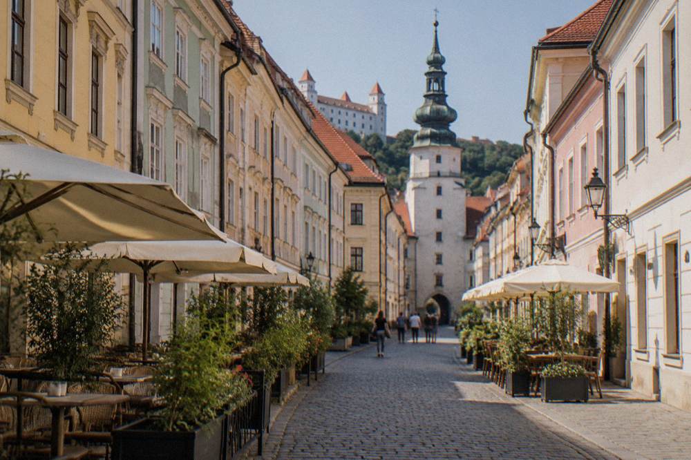 Narrow pedestrian street in Bratislava Old Town lined with pastel townhouses and restaurants
