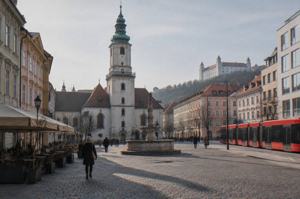 A red tram passing modern buildings on a Bratislava street